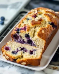 Freshly baked blueberry bread loaf with blueberries on a wooden table